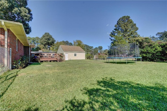 view of yard with a trampoline and a deck