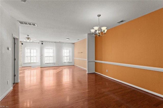 unfurnished room with hardwood / wood-style floors and ceiling fan with notable chandelier