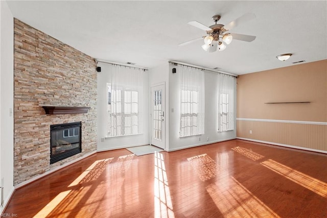 unfurnished living room featuring a stone fireplace, ceiling fan, and light hardwood / wood-style floors