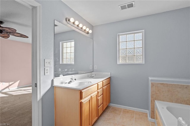 bathroom featuring tile patterned floors, a wealth of natural light, a washtub, and vanity