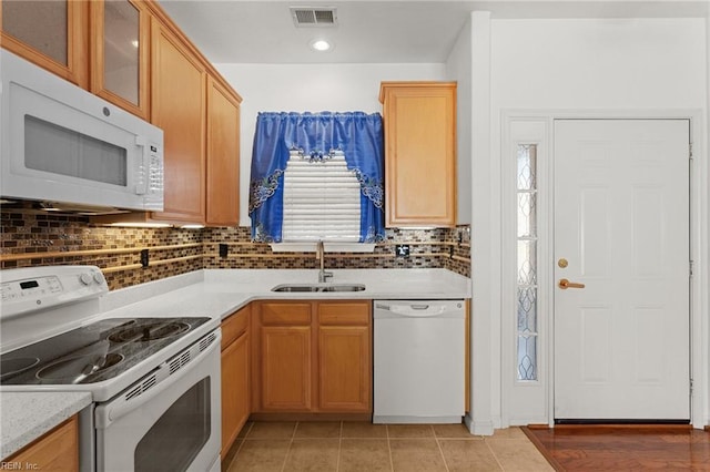 kitchen featuring light stone countertops, tasteful backsplash, white appliances, sink, and light tile patterned flooring