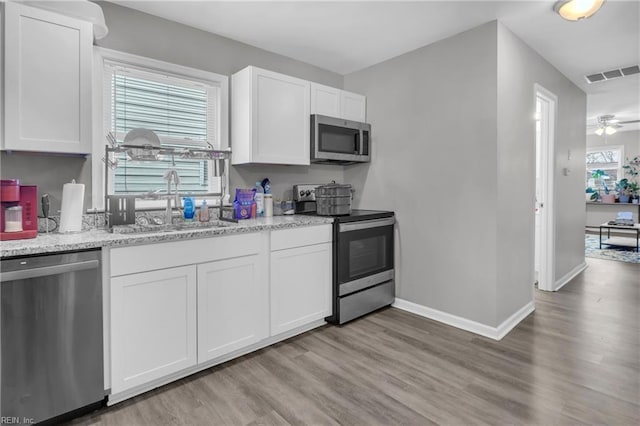 kitchen with light stone counters, sink, white cabinets, and appliances with stainless steel finishes