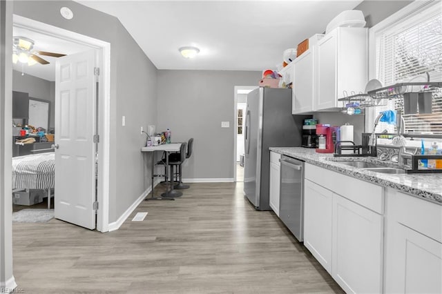 kitchen featuring light stone counters, stainless steel appliances, ceiling fan, light hardwood / wood-style floors, and white cabinetry