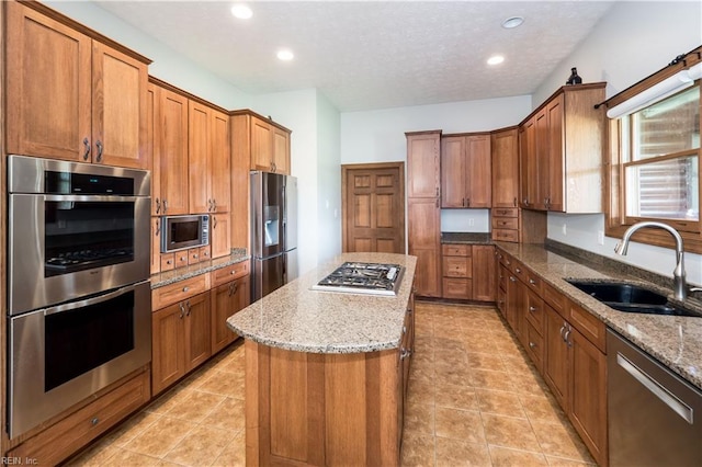 kitchen with light stone countertops, sink, a kitchen island, and stainless steel appliances