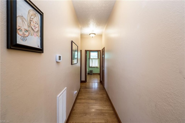 corridor with wood-type flooring and a textured ceiling