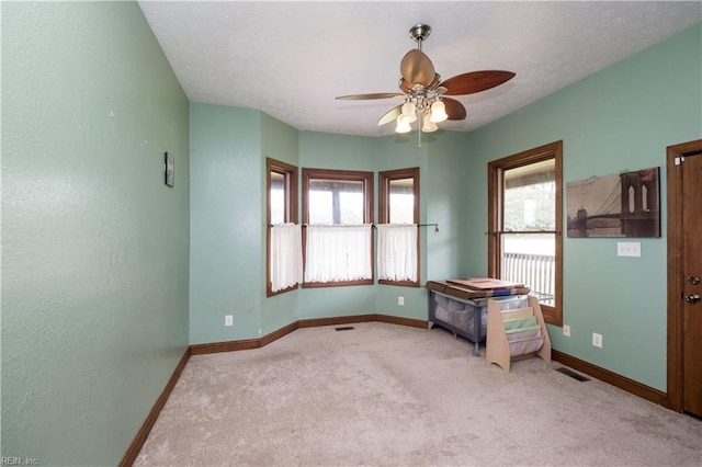 unfurnished bedroom featuring ceiling fan, light carpet, and a textured ceiling