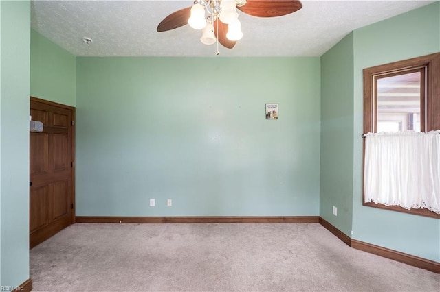 empty room with ceiling fan, light colored carpet, and a textured ceiling