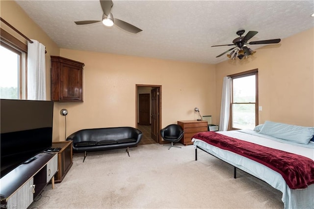 carpeted bedroom featuring ceiling fan, a textured ceiling, and multiple windows