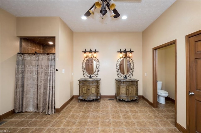 bathroom with ceiling fan, vanity, a textured ceiling, and toilet