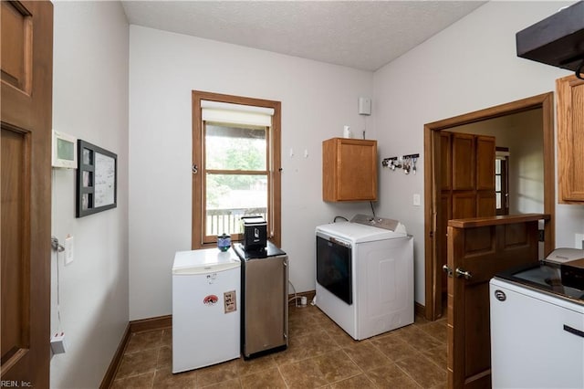 laundry area featuring cabinets, a textured ceiling, and washing machine and dryer