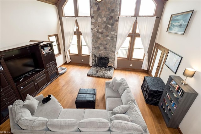 living room featuring a stone fireplace and light wood-type flooring