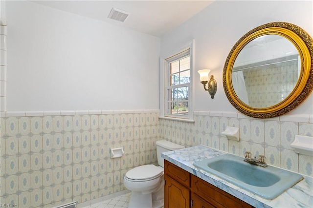 bathroom with tile patterned flooring, vanity, toilet, and tile walls