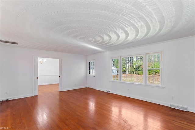 empty room featuring hardwood / wood-style floors and a chandelier