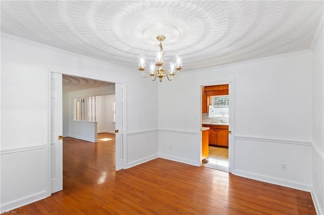 unfurnished room featuring ornamental molding, sink, light wood-type flooring, and an inviting chandelier