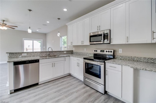 kitchen featuring pendant lighting, sink, white cabinetry, kitchen peninsula, and stainless steel appliances