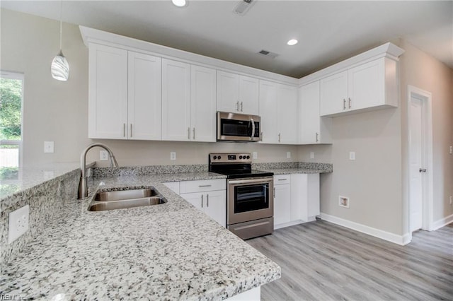 kitchen with white cabinetry, sink, stainless steel appliances, light stone counters, and decorative light fixtures