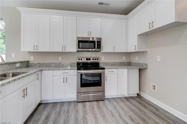 kitchen with sink, white cabinets, light hardwood / wood-style floors, and appliances with stainless steel finishes