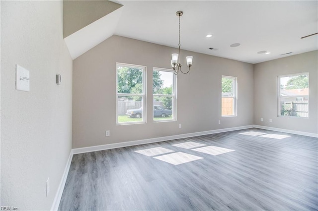 unfurnished dining area featuring plenty of natural light, lofted ceiling, dark wood-type flooring, and an inviting chandelier