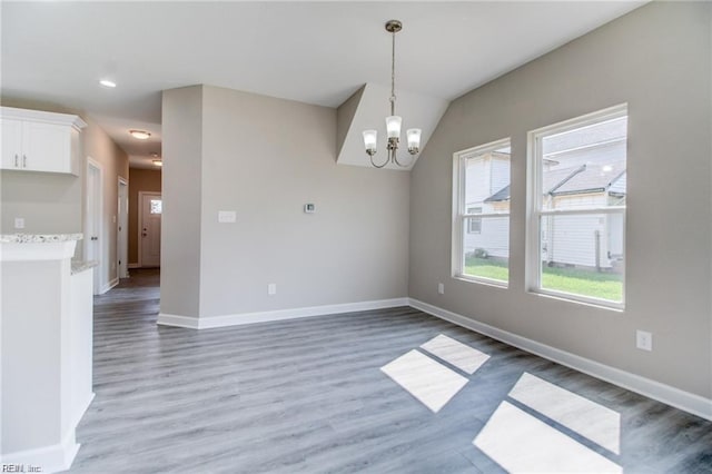 unfurnished room featuring dark hardwood / wood-style flooring, vaulted ceiling, and an inviting chandelier