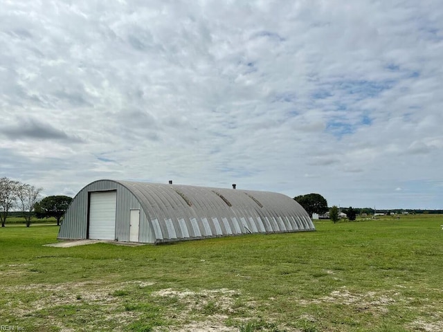 view of outdoor structure featuring a yard, a rural view, and a garage