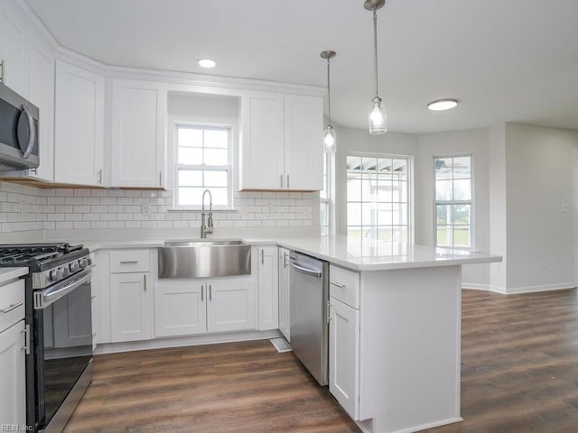 kitchen with kitchen peninsula, sink, white cabinets, and appliances with stainless steel finishes