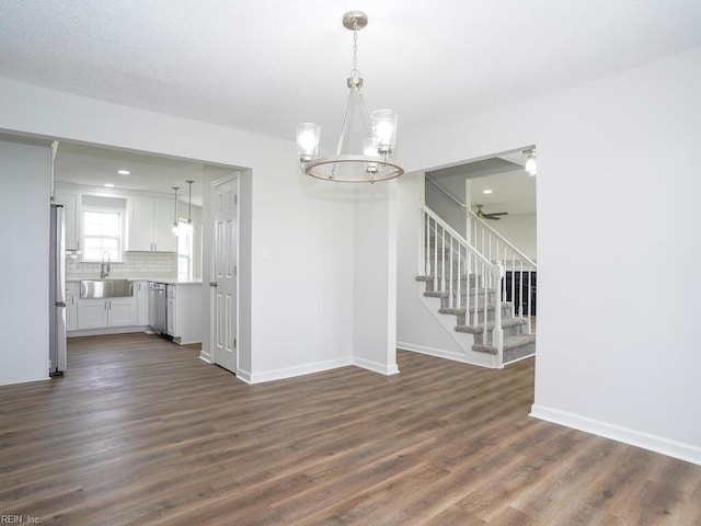 unfurnished dining area with ceiling fan with notable chandelier, dark hardwood / wood-style flooring, and sink