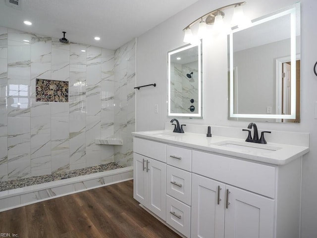 bathroom featuring hardwood / wood-style floors, vanity, and tiled shower