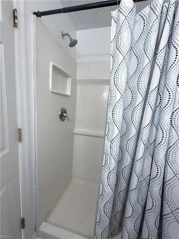 bathroom featuring a shower with shower curtain and a textured ceiling