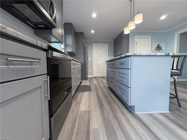 kitchen featuring a kitchen breakfast bar, ornamental molding, pendant lighting, light hardwood / wood-style flooring, and stone counters