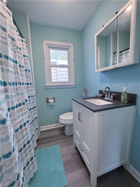 bathroom featuring toilet, vanity, a shower with shower curtain, and hardwood / wood-style flooring