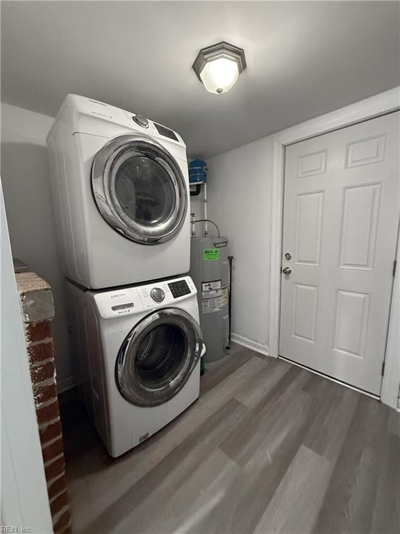 laundry room featuring water heater, stacked washer and clothes dryer, and hardwood / wood-style flooring