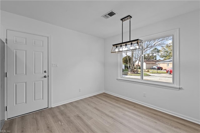 unfurnished dining area featuring a chandelier and light hardwood / wood-style floors