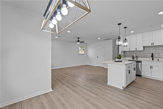 kitchen featuring white cabinetry, sink, a kitchen island, and hanging light fixtures