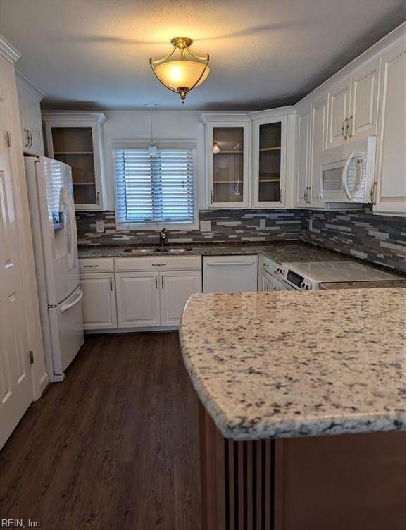 kitchen with white appliances, sink, hanging light fixtures, light stone counters, and white cabinetry