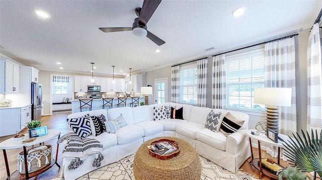 living room with crown molding, ceiling fan, and light hardwood / wood-style floors