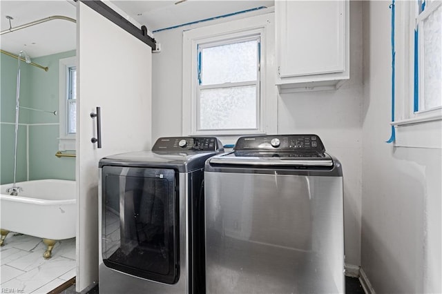 clothes washing area with cabinets, a barn door, and separate washer and dryer