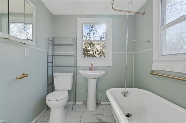 bathroom with a bathing tub, plenty of natural light, toilet, and sink