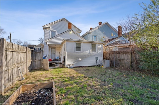 back of house with central air condition unit and a lawn