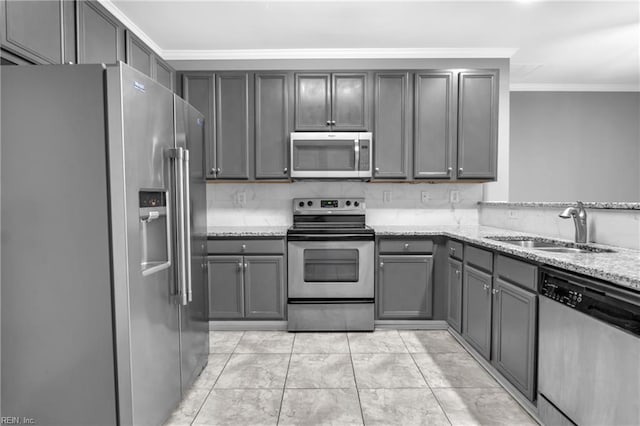 kitchen with stainless steel appliances, light stone counters, gray cabinetry, and sink