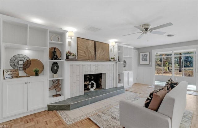 living room featuring ceiling fan, light parquet floors, and a tiled fireplace