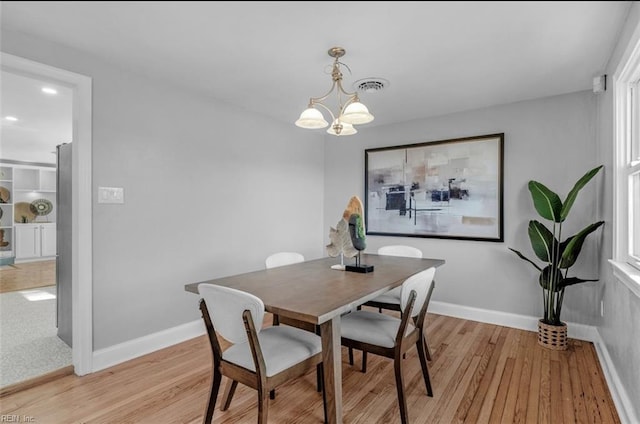 dining space featuring light hardwood / wood-style flooring and a chandelier