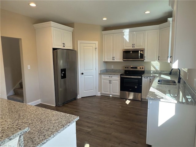 kitchen with light stone countertops, sink, white cabinetry, and stainless steel appliances