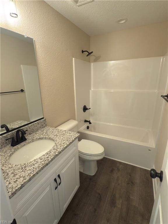 full bathroom featuring shower / bathtub combination, vanity, a textured ceiling, hardwood / wood-style floors, and toilet