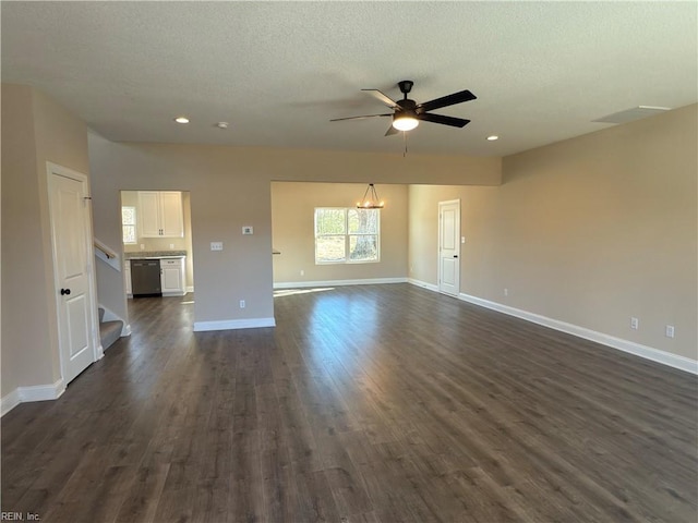 unfurnished living room featuring ceiling fan with notable chandelier, dark hardwood / wood-style flooring, and a textured ceiling