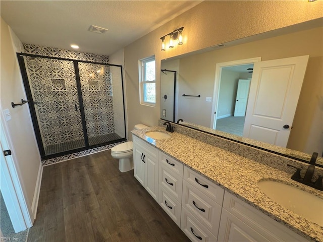 bathroom with hardwood / wood-style flooring, vanity, toilet, and a shower with door