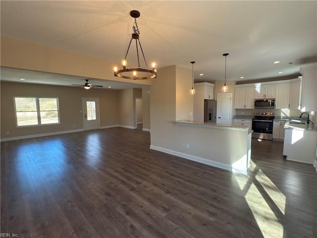 kitchen with pendant lighting, dark wood-type flooring, white cabinets, appliances with stainless steel finishes, and kitchen peninsula