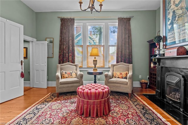 living area featuring hardwood / wood-style flooring, a wood stove, and an inviting chandelier