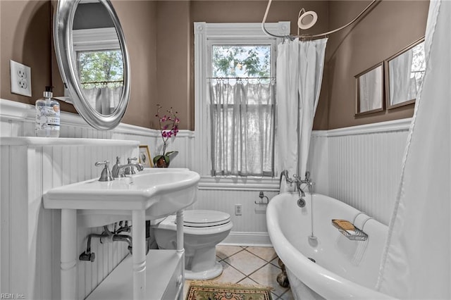 bathroom featuring tile patterned floors, a washtub, plenty of natural light, and toilet