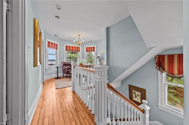 corridor featuring plenty of natural light, light hardwood / wood-style flooring, and a chandelier