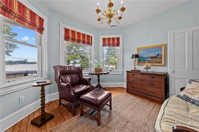 sitting room with wood-type flooring, a wealth of natural light, and a chandelier